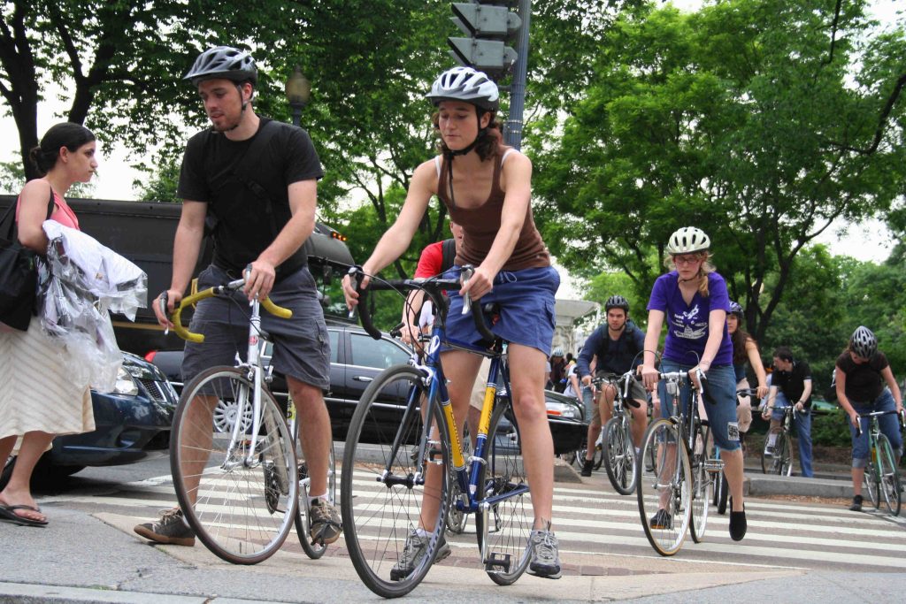 Bike riders ride across a street